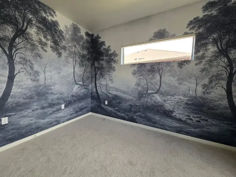 Blue-grey landscape mural of trees wrapping around the inside corner of a room